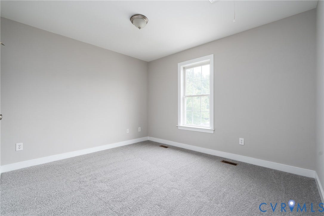 Neutral wall paint, light-colored carpeting, white trim, and a window with white casing