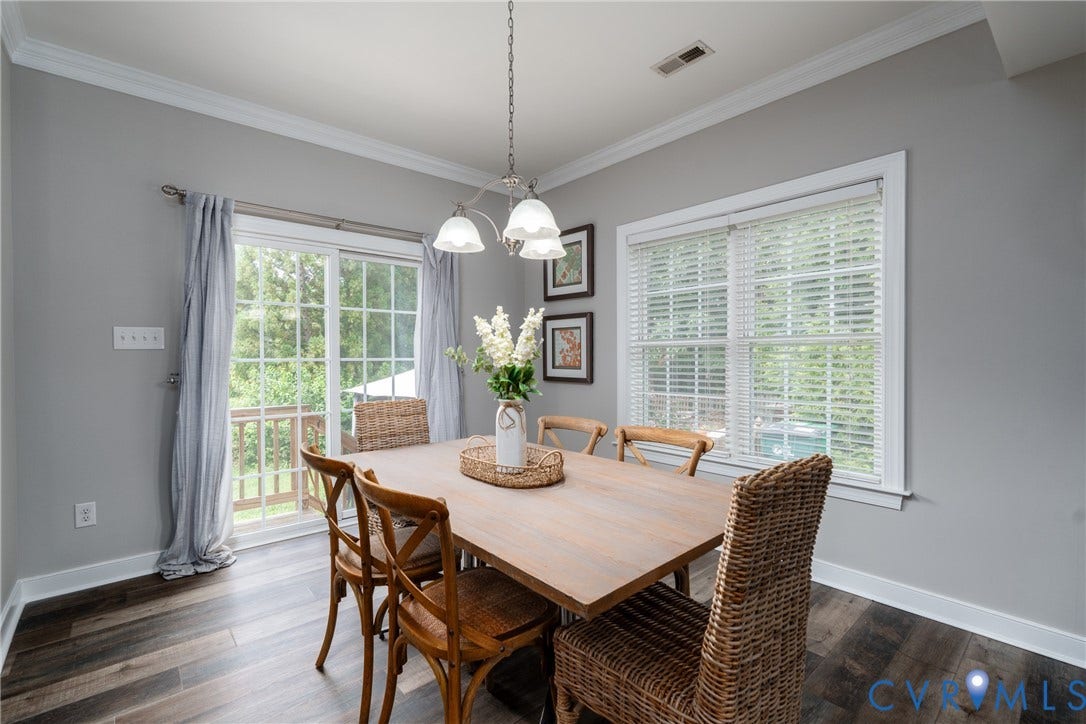Wood-finish flooring with white trim, a three-light pendant fixture, and a sliding glass door