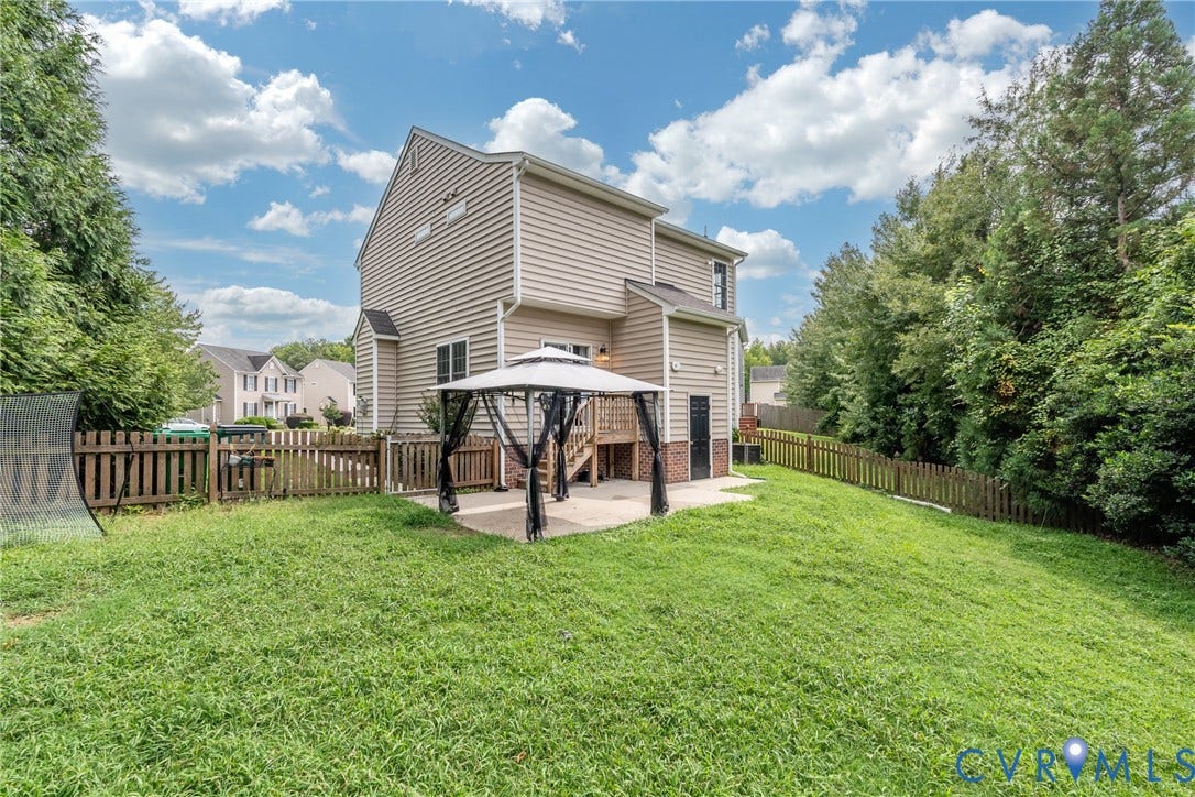 Expansive backyard featuring a manicured lawn, established privacy trees, and a wooden picket fence