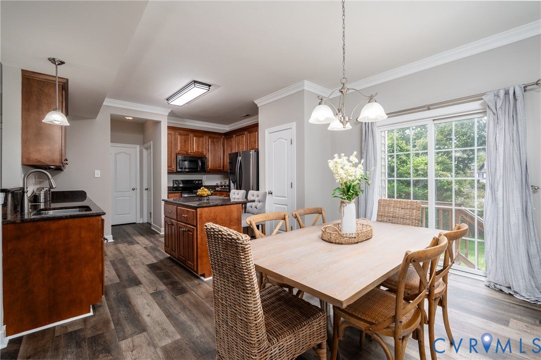 Wood-finish flooring, sliding glass door, crown molding, kitchen island with built-in cabinetry, and pendant lighting