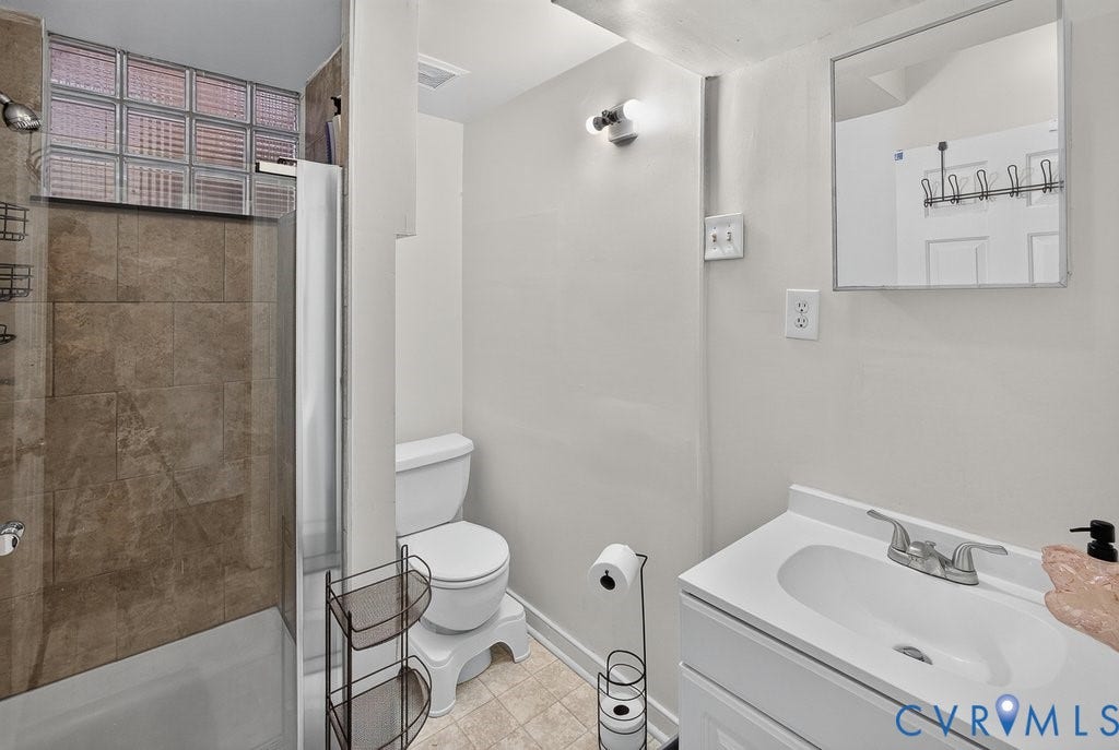 1826 Idlewood Avenue, Randolph, Richmond, VA 23220 Tile-surround shower with a glass block window, white vanity with integrated sink, and wall-mounted mirror
