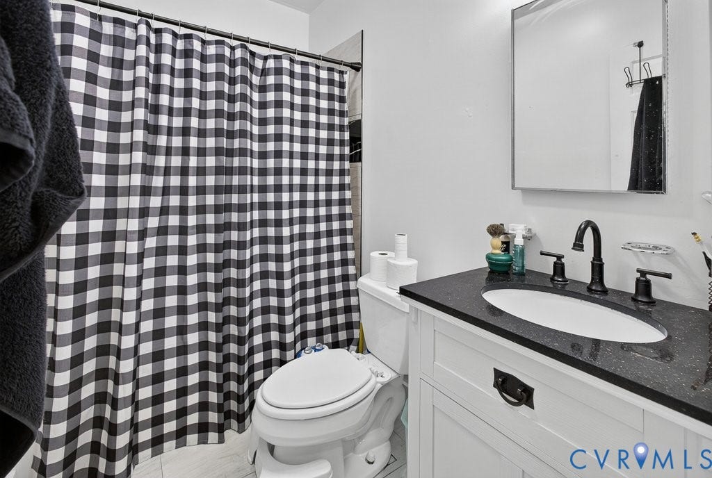 1826 Idlewood Avenue, Randolph, Richmond, VA 23220 White vanity with black countertop and undermount sink, complemented by a wall-mounted medicine cabinet and a toilet