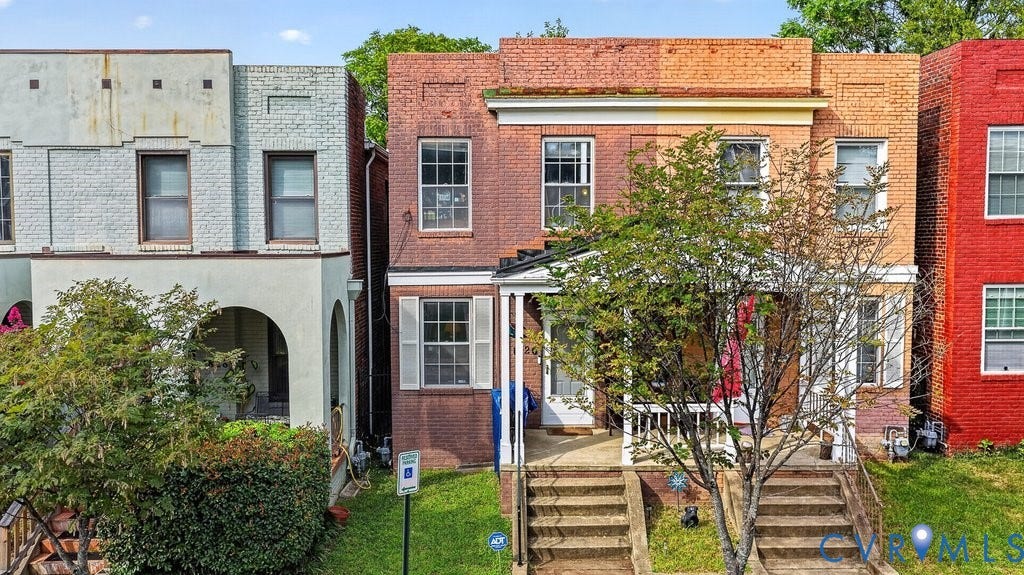 1826 Idlewood Avenue, Randolph, Richmond, VA 23220 Brick exterior with white window shutters and a covered front porch, featuring concrete steps leading to the entrance