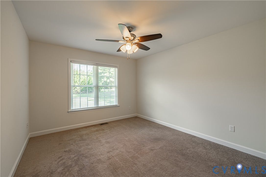 Neutral tone wall color, window with blinds, ceiling fan with integrated lighting, and carpeted flooring