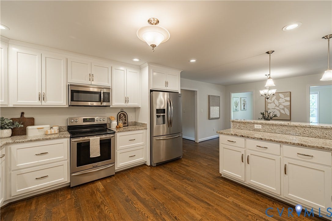 White cabinetry, stainless steel appliances, light-toned countertops, wood-finish flooring, and recessed lighting