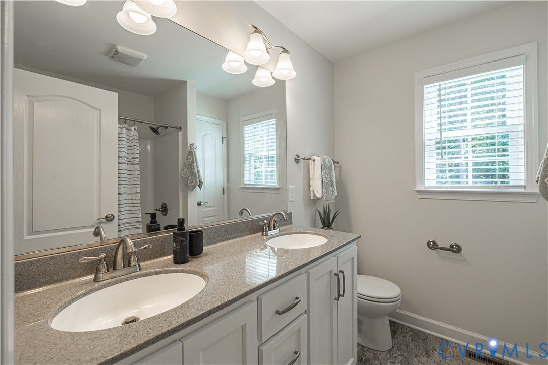 Dual vanity with undermount sinks, stone-finish countertop, and brushed nickel fixtures