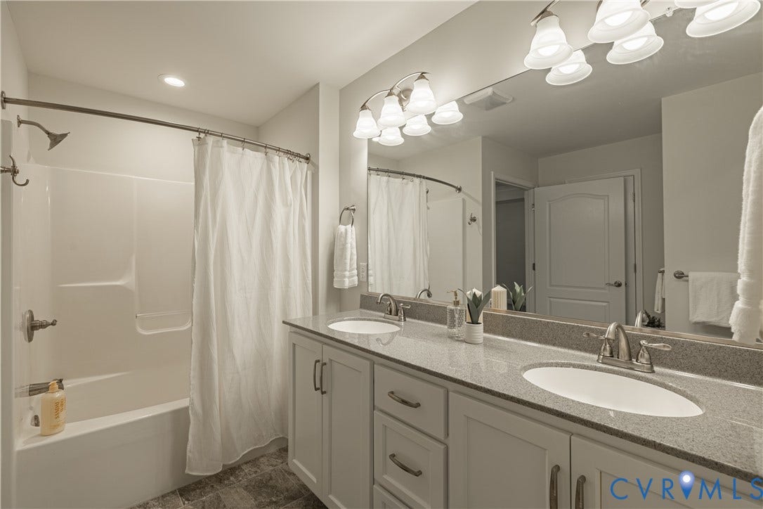 Double vanity with granite-style countertops, white cabinetry, and brushed nickel fixtures