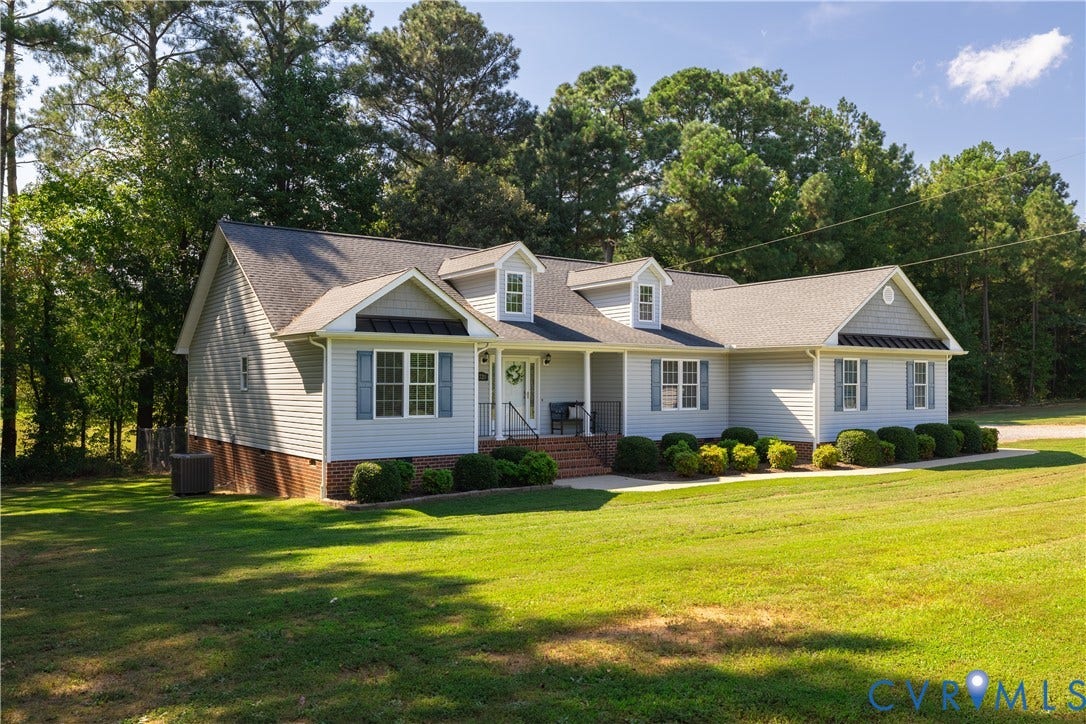 Light-colored siding exterior with a dark shingle roof and brick foundation