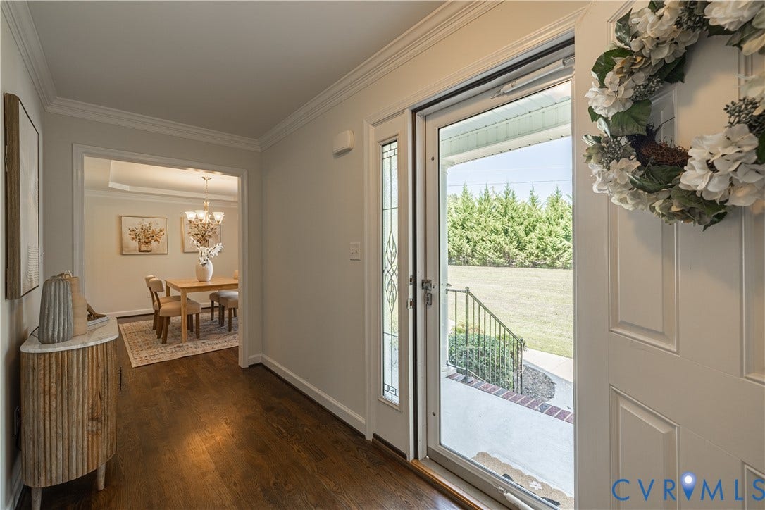 Hardwood-finish flooring throughout, crown molding detailing, and a leaded glass sidelight flanking the entryway