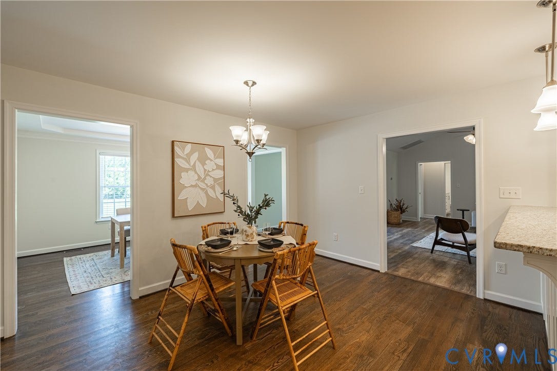 Wood-finish flooring throughout, tray ceiling in an adjoining room, and a chandelier lighting fixture