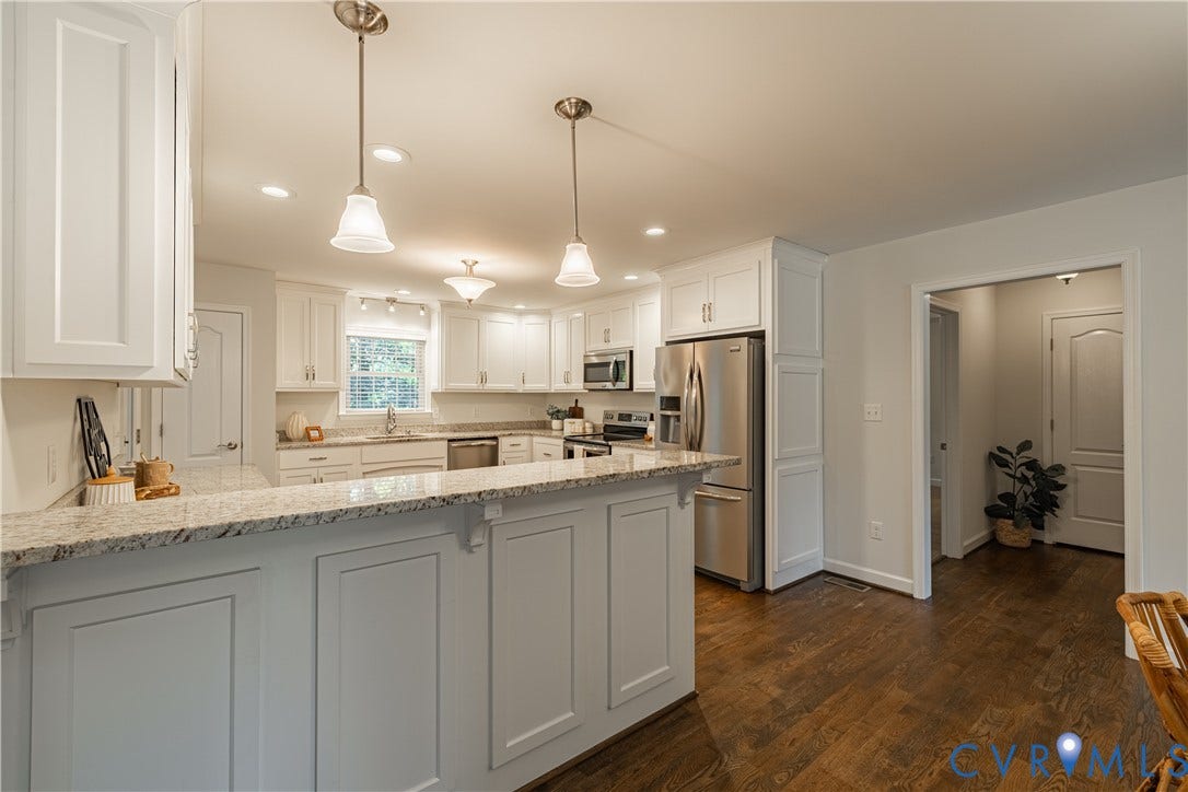 Kitchen with white shaker cabinetry, stainless steel appliances, granite countertops, and wood-finish flooring