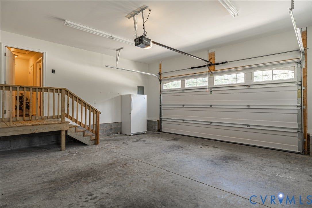 Attached garage featuring a concrete floor, built-in wooden staircase, and garage door with upper-level windows