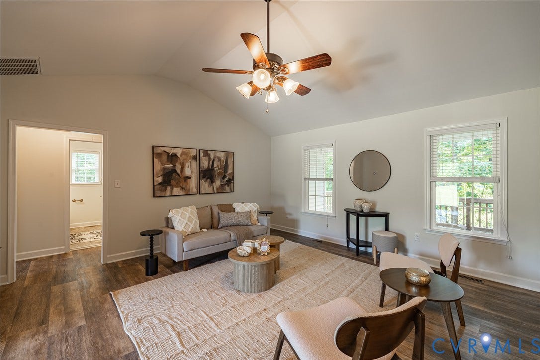 Vaulted ceiling with a ceiling fan, wood-finish flooring, and multiple windows