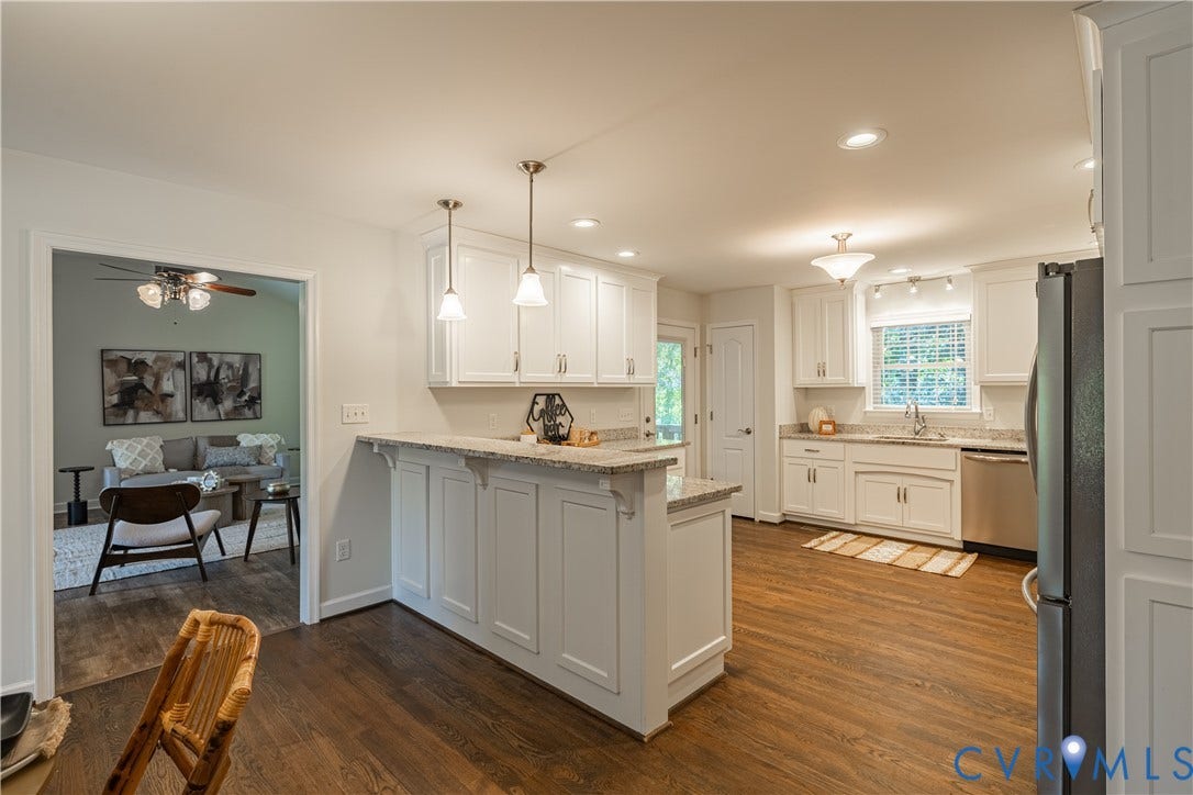 Expansive kitchen featuring wood-finish flooring, white cabinetry, recessed lighting, and granite countertops