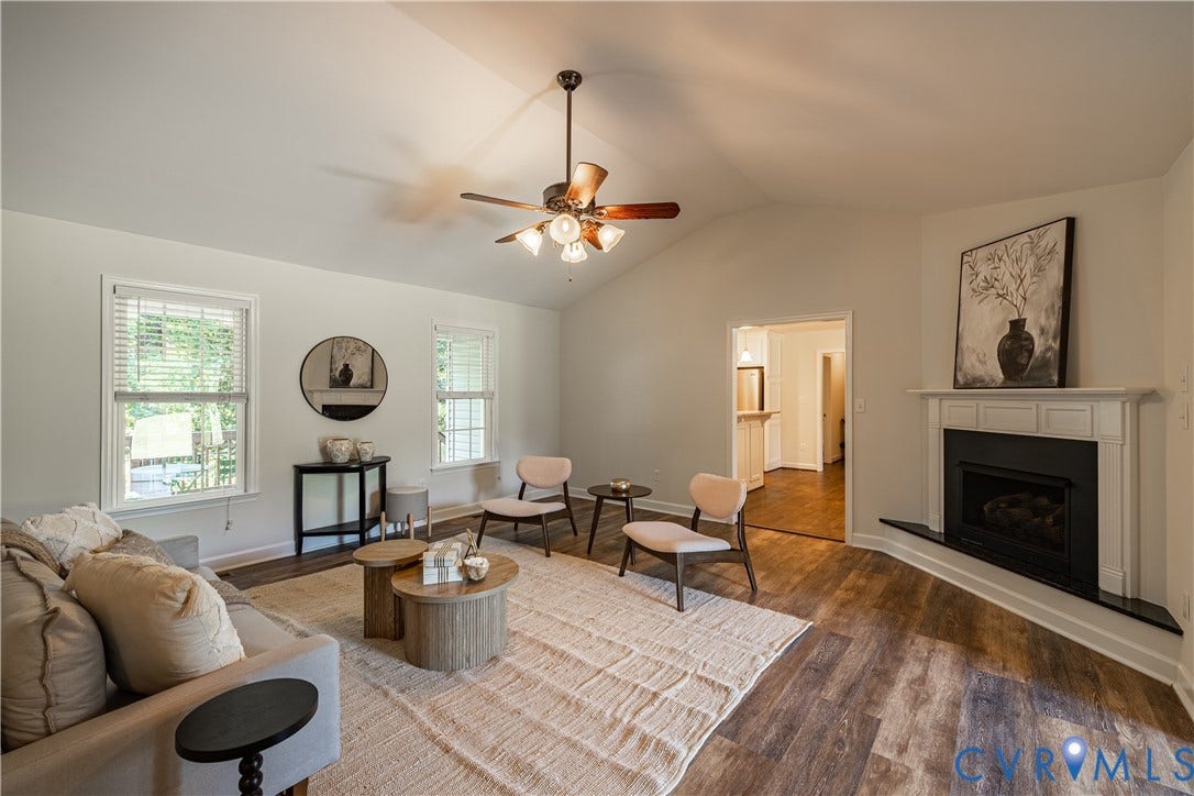 Vaulted ceiling, wood-finish flooring, white mantel, built-in fireplace, and ceiling fan with integrated lighting