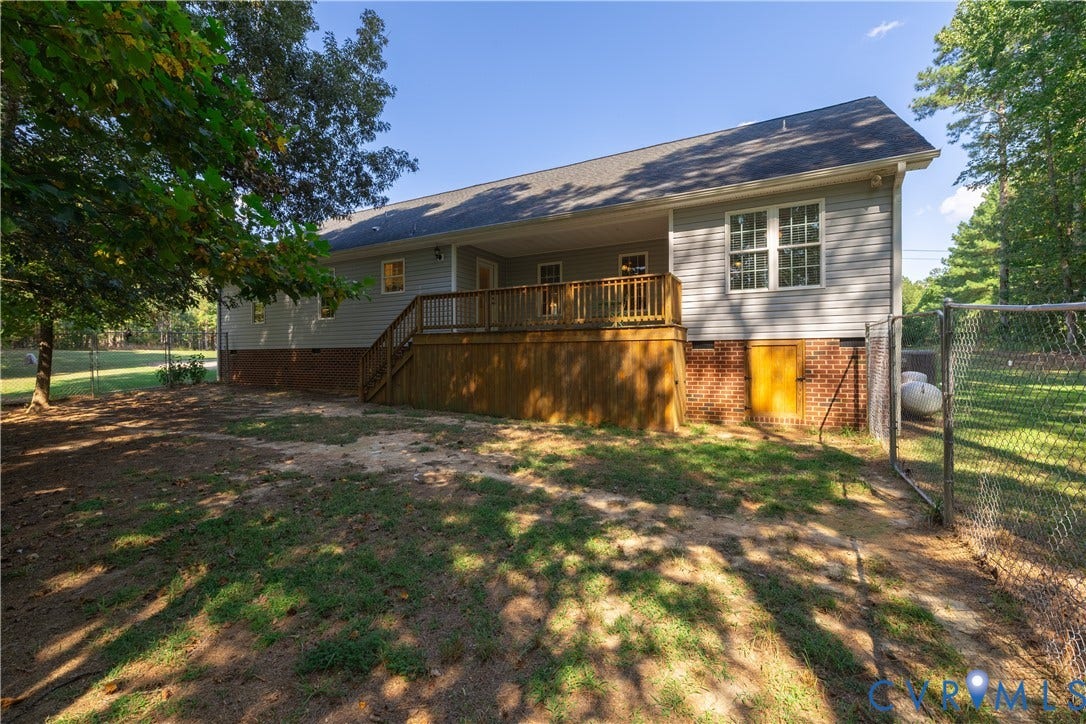 Backyard featuring a wood deck, chain-link fencing, and mature trees