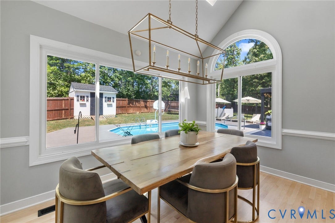 Vaulted ceiling, oversized windows, arched window, gold-finish chandelier, and wood-finish flooring