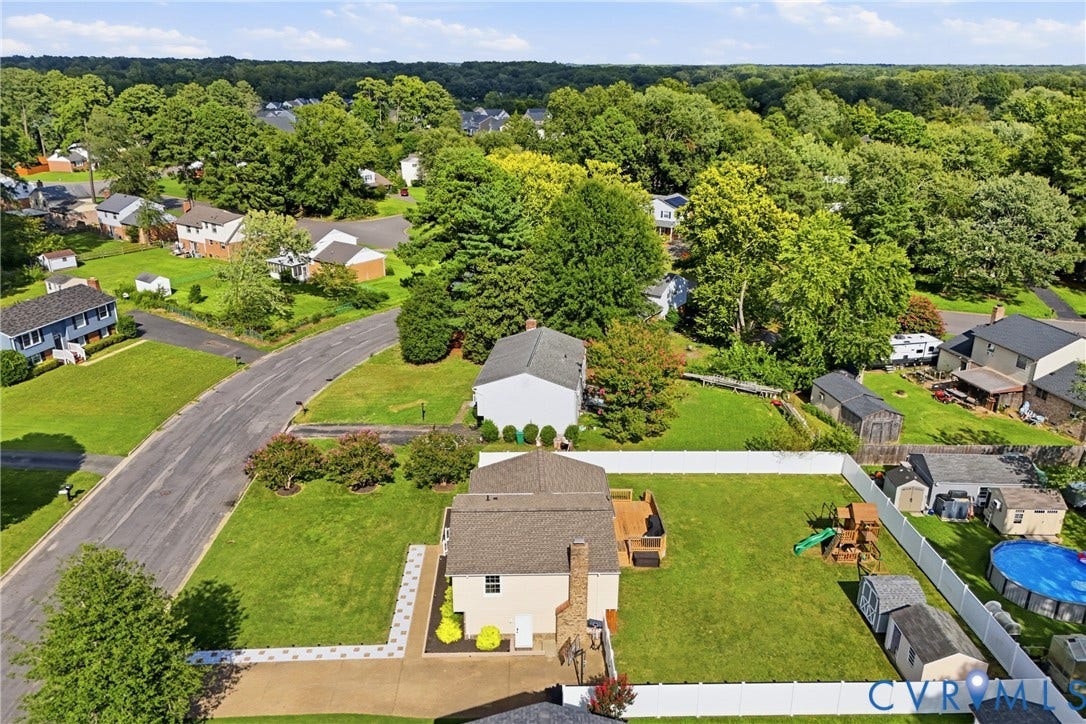 1905 Reagan Road, Henrico, VA 23228 Expansive fenced backyard with a wood deck, multiple storage sheds, and a paved patio area