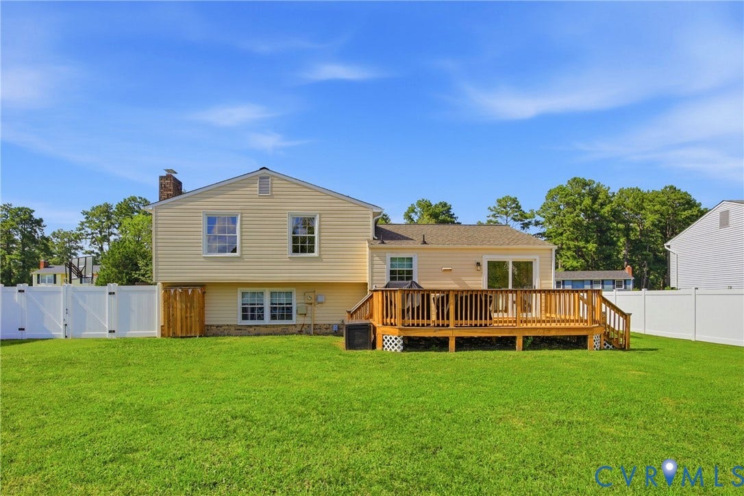 1905 Reagan Road, Henrico, VA 23228 Expansive backyard featuring a manicured lawn, a large wood deck with railings, vinyl siding, and a white privacy fence