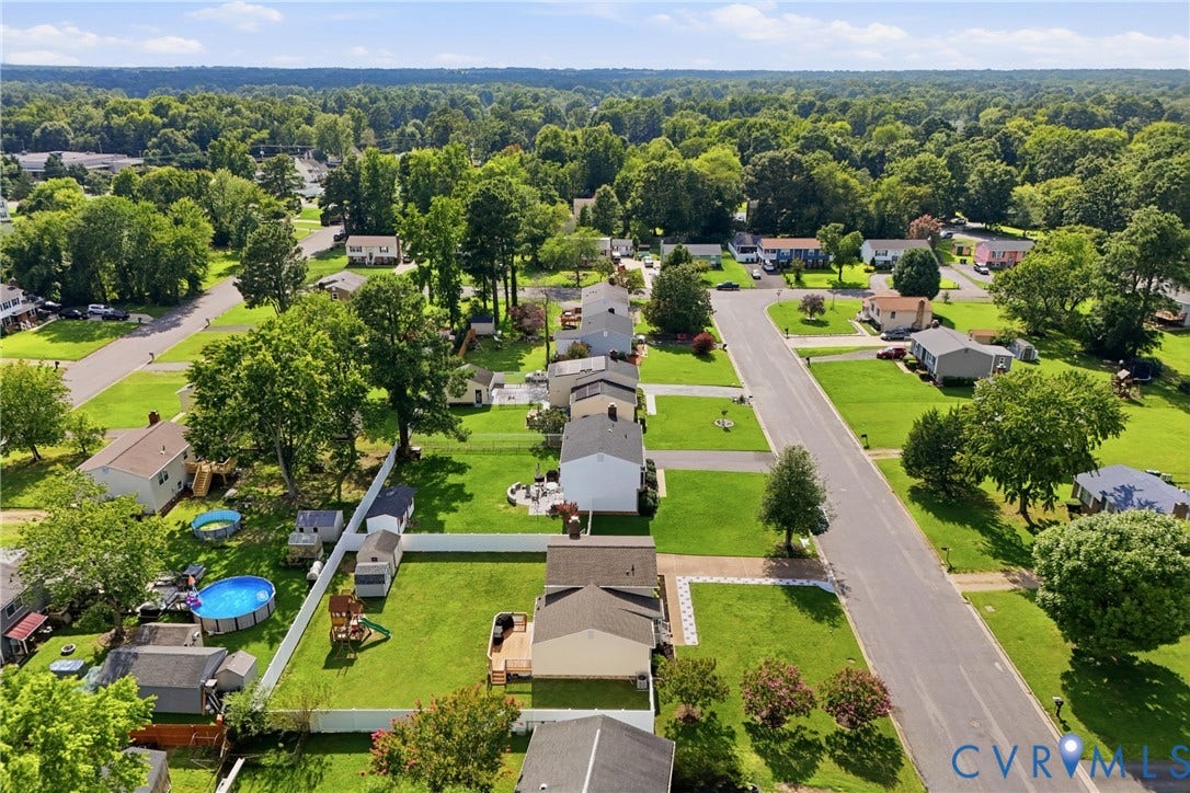 1905 Reagan Road, Henrico, VA 23228 Residential streetscape featuring single-story homes, expansive green lawns, mature trees, and paved roadways