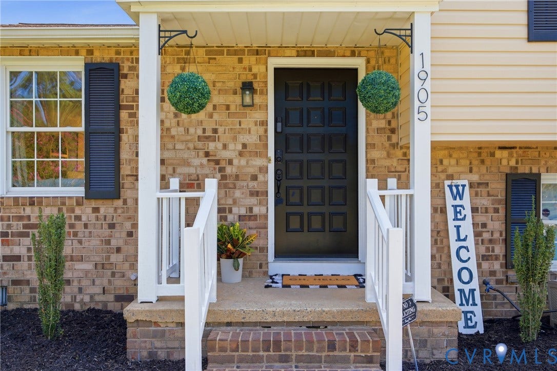 1905 Reagan Road, Henrico, VA 23228 Brick exterior with white trim, featuring a dark paneled entry door and a white railing on the front steps