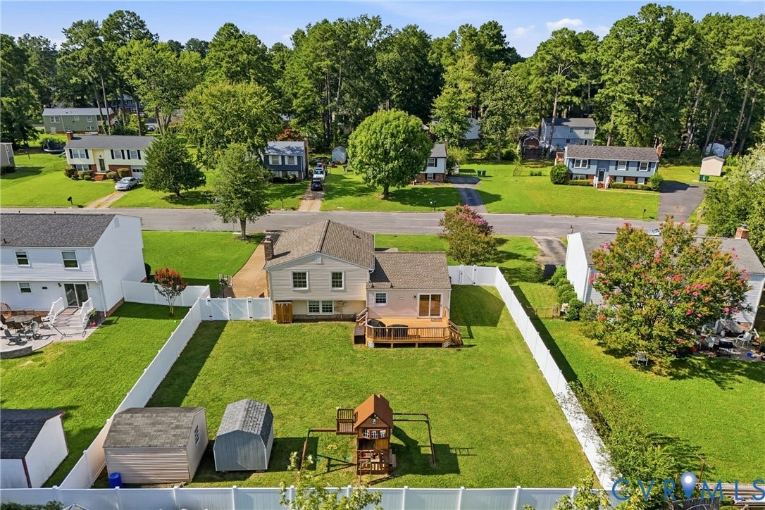 1905 Reagan Road, Henrico, VA 23228 Expansive backyard featuring a manicured lawn, white privacy fencing, and two storage sheds