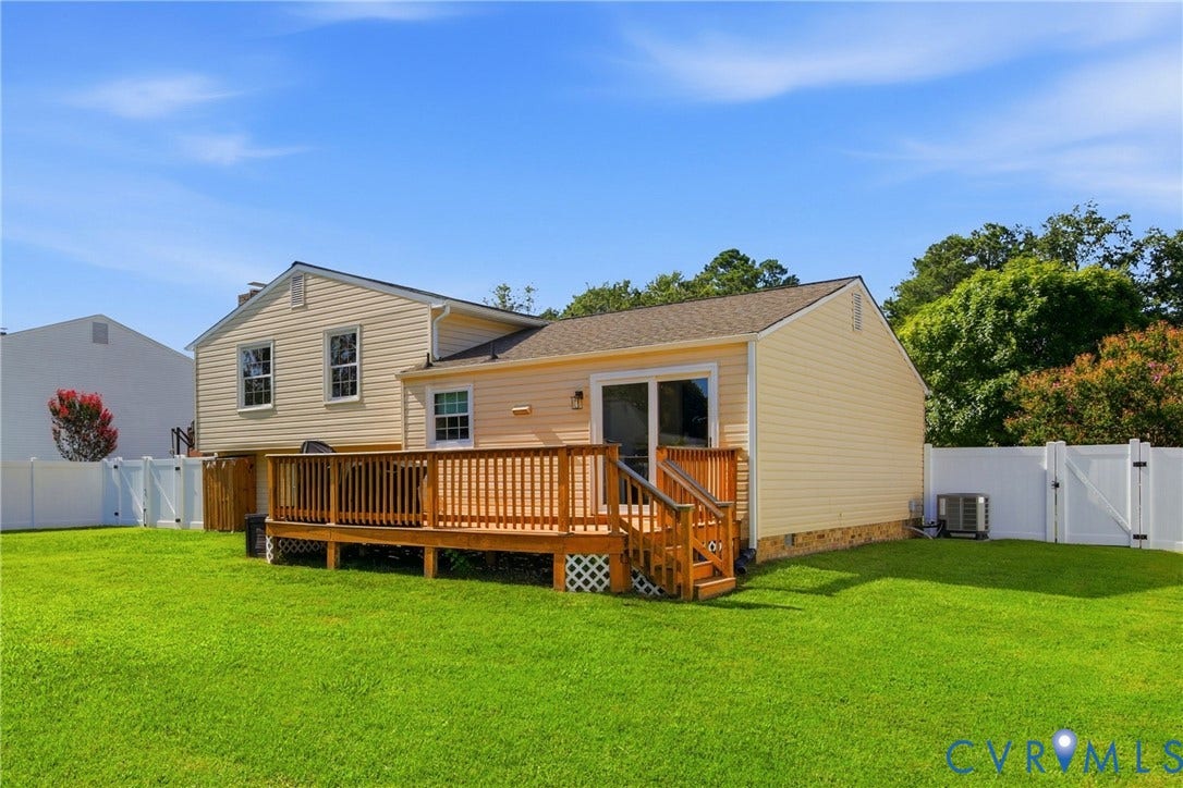 1905 Reagan Road, Henrico, VA 23228 Expansive green lawn featuring a wood deck with railings, vinyl privacy fencing, and sliding glass door access