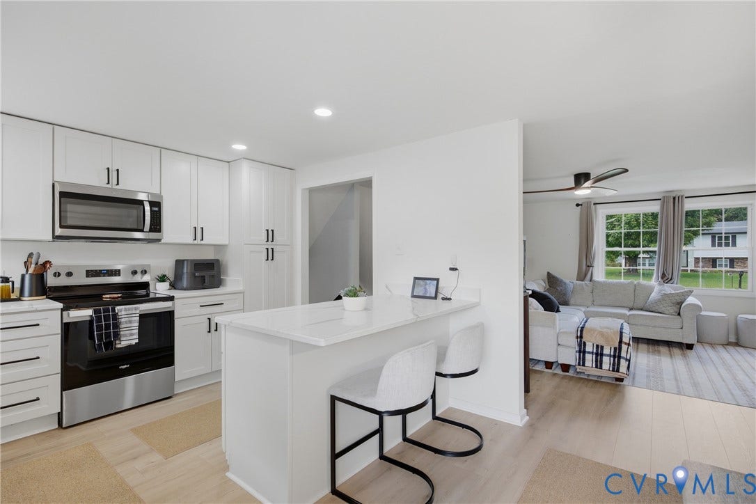 1905 Reagan Road, Henrico, VA 23228 White shaker cabinetry with black hardware, stainless steel appliances, light wood-finish flooring, recessed lighting, and a kitchen island with a white countertop