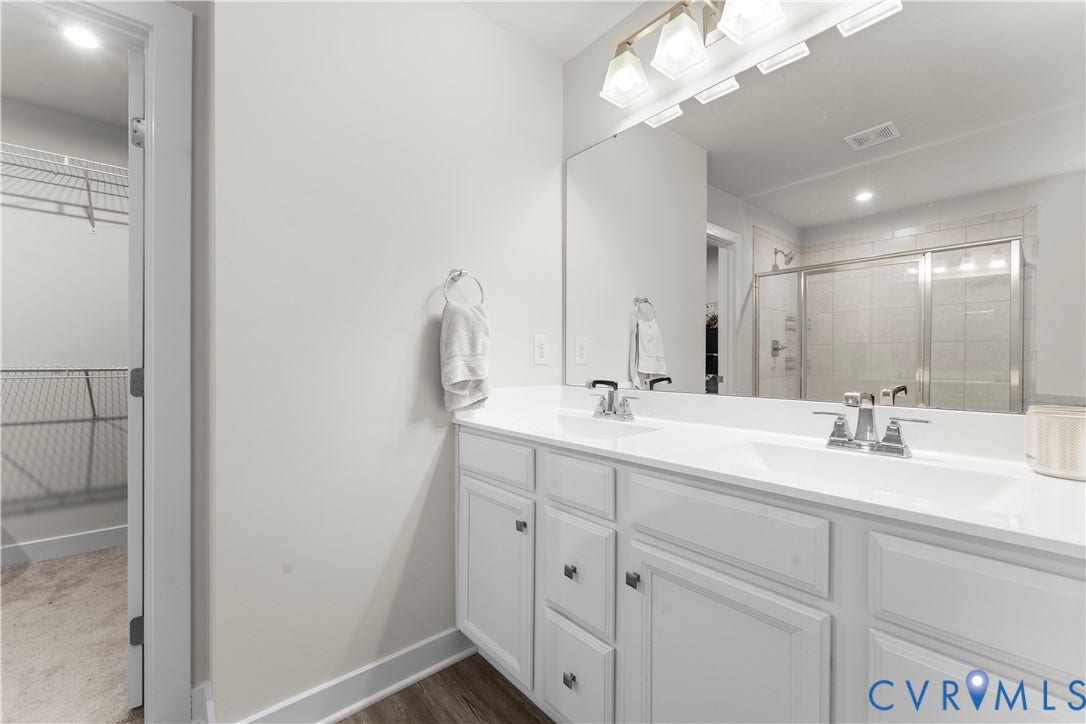 11707 Amara Drive, Chester / Highlands Golf Club, Chesterfield, VA 23838 Double vanity with white cabinetry and integrated sinks, extensive mirror, and a walk-in shower with subway tile