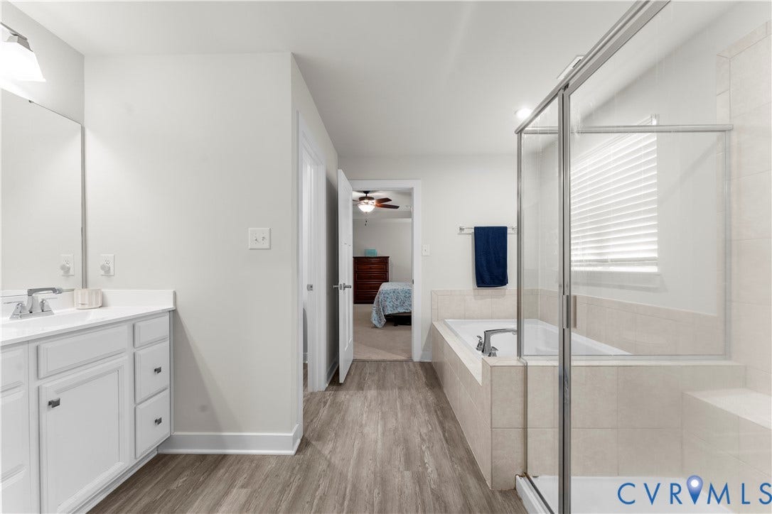 11707 Amara Drive, Chester / Highlands Golf Club, Chesterfield, VA 23838 Bathroom featuring a single vanity with storage, a large soaking tub, a separate glass-enclosed shower, and wood-finish flooring