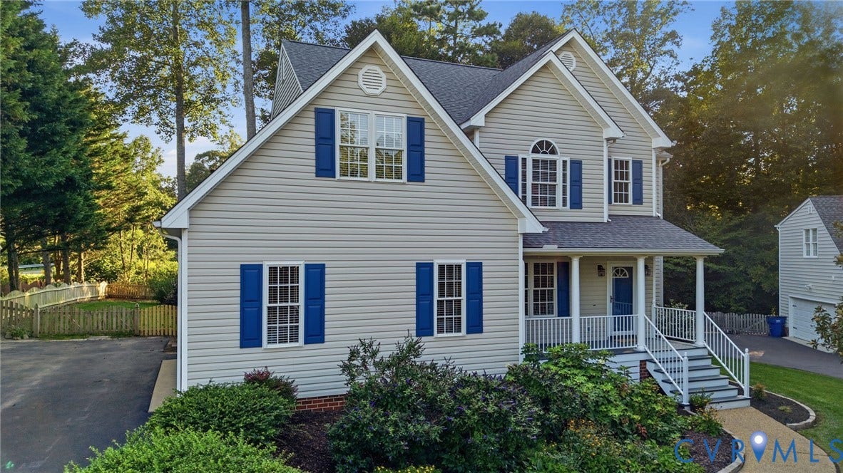 Two-story residence featuring light-toned siding, a covered front porch, and vibrant blue window shutters