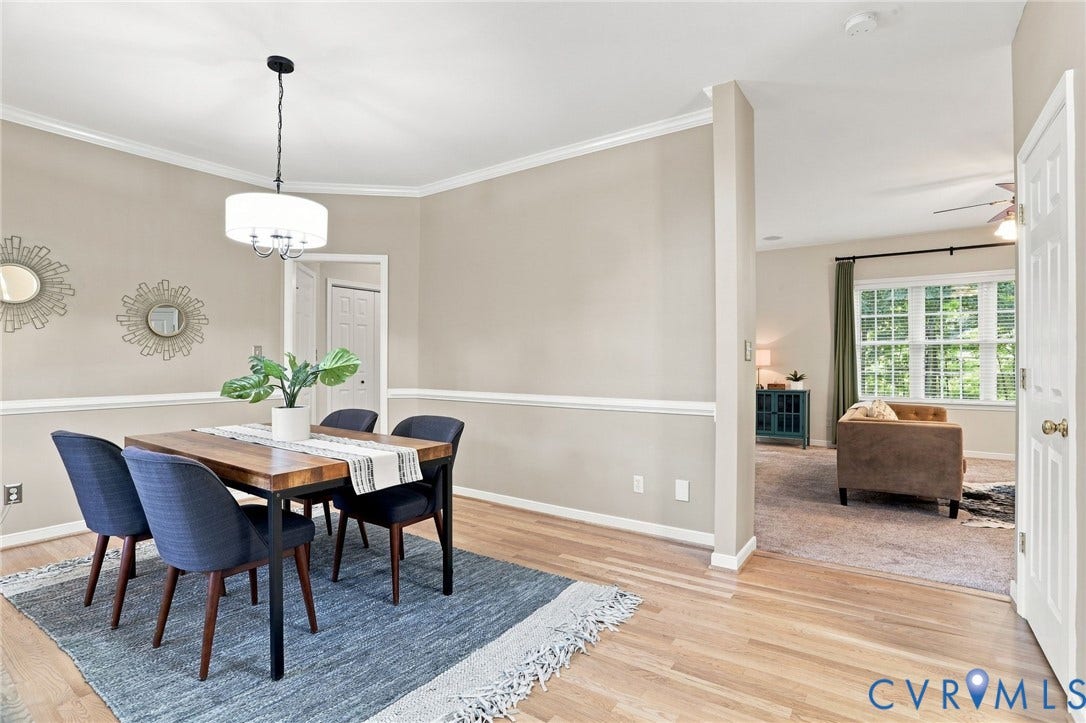 Hardwood flooring with crown molding and chair rail detailing, complemented by a contemporary drum pendant light fixture