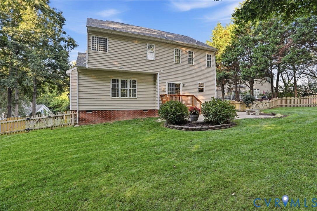 Expansive backyard featuring a manicured lawn, picket fencing, and mature trees