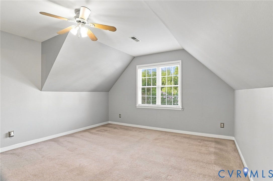 Carpeted room featuring a ceiling fan, sloped ceilings, and a window with blinds