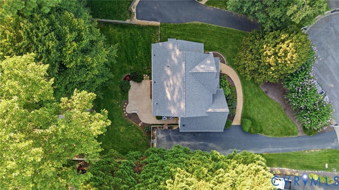 Expansive lot with mature trees, manicured lawn, and paved driveway