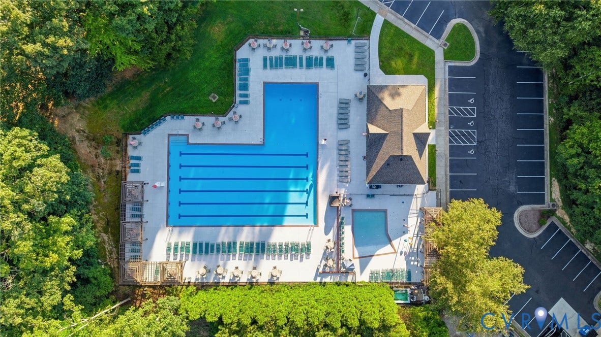 Community swimming pool featuring lap lanes, an adjacent children's pool, and a poolside building with a multi-gabled roof
