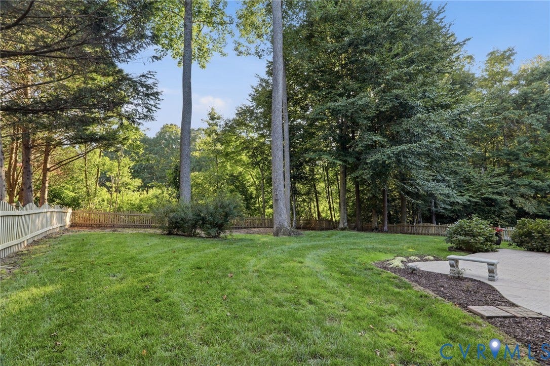 Expansive lawn with mature trees and a privacy fence