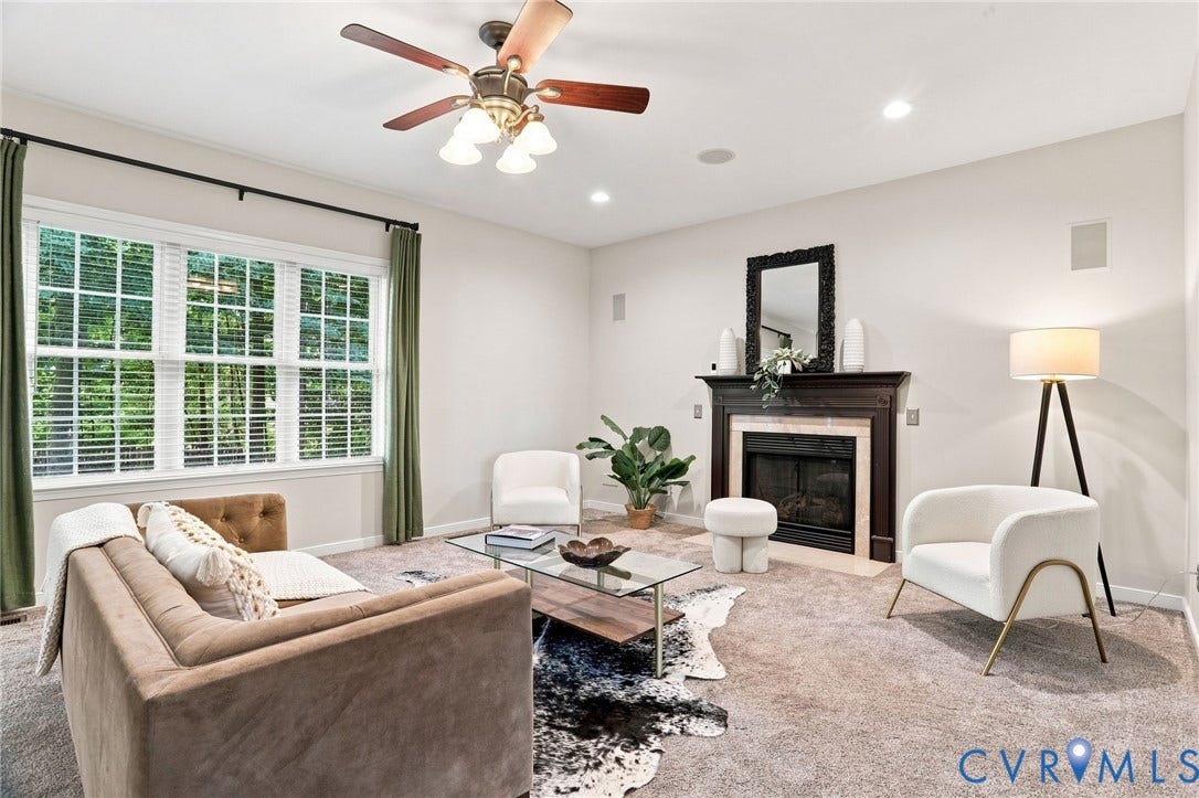 Carpeted living area featuring a fireplace with a dark wood mantel, a multi-pane window with blinds, a ceiling fan with integrated lighting, and recessed lighting