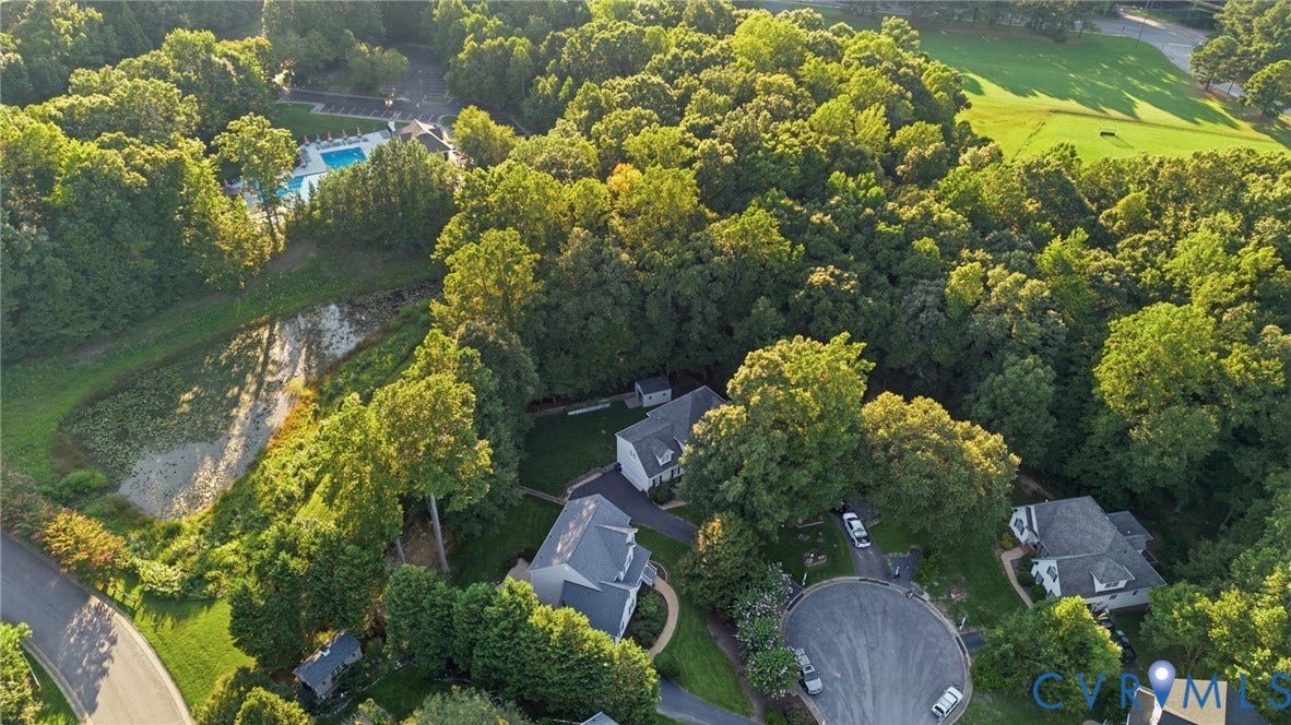 Aerial perspective showcasing a cul-de-sac, multiple residential properties, and extensive mature trees