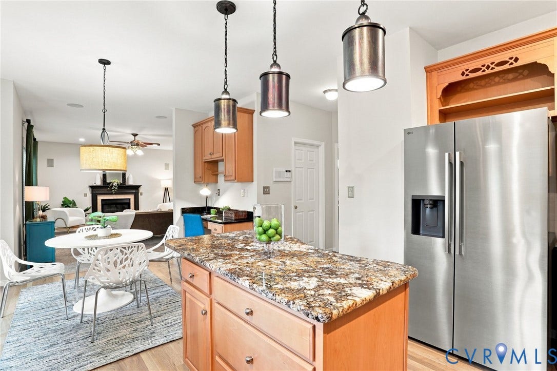 Kitchen island with stone countertop, stainless steel refrigerator, and recessed lighting