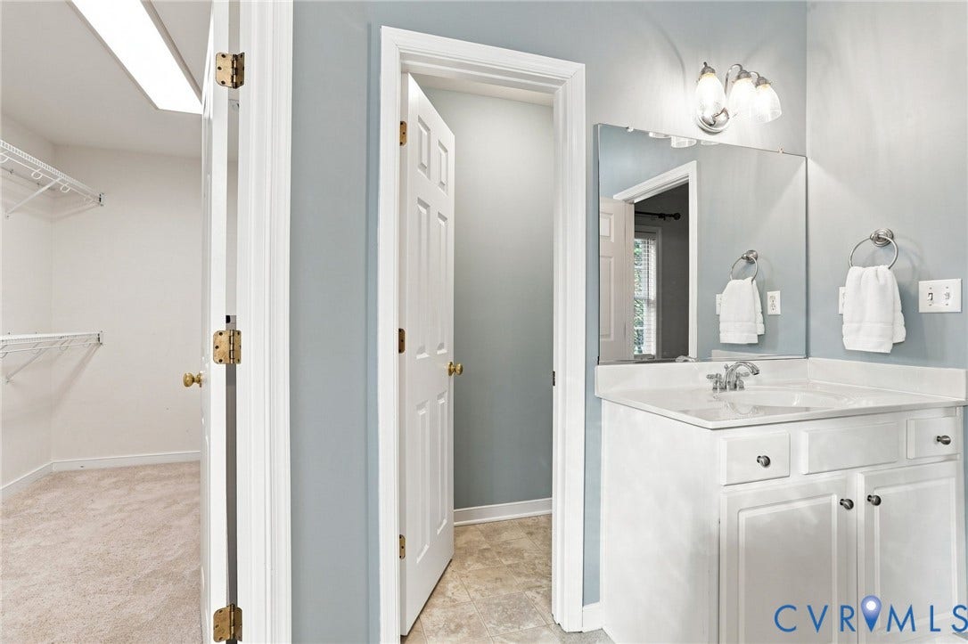 Bathroom featuring a single vanity with an integrated sink, polished chrome faucet, and a wall-mounted mirror