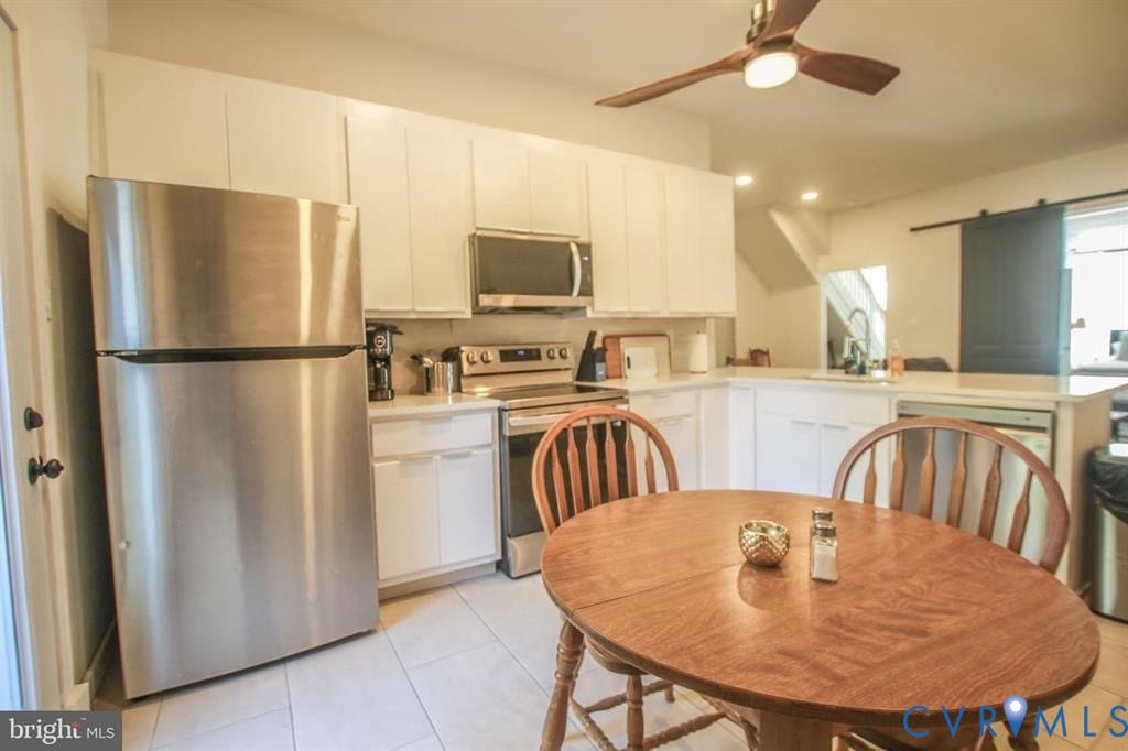 1910 W Main Street, The Historic Fan District, Richmond, VA 23220 White cabinetry with stainless steel appliances, light-toned countertops, and wood-finish ceiling fan