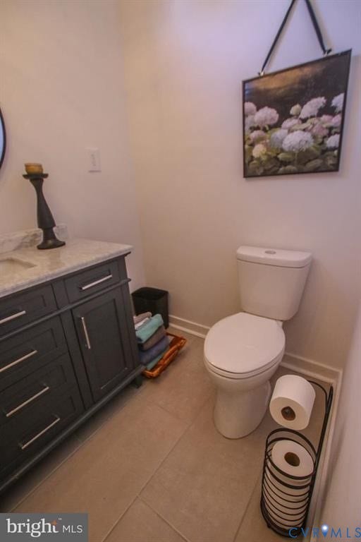 1910 W Main Street, The Historic Fan District, Richmond, VA 23220 White two-piece toilet with a soft-close lid, dark gray vanity with chrome hardware, light-colored countertop, and square floor tiles