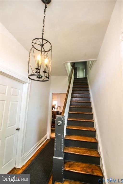 1910 W Main Street, The Historic Fan District, Richmond, VA 23220 Open staircase with wood treads and a dark banister, complemented by a contemporary chandelier