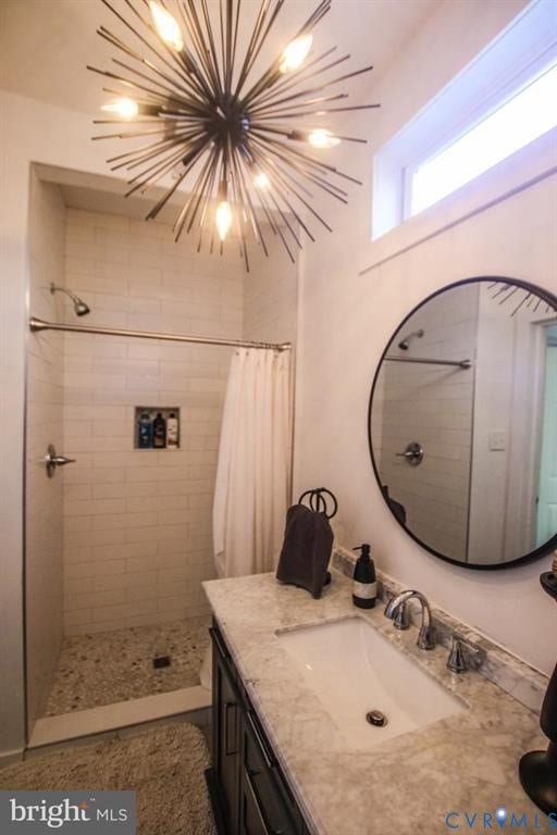 1910 W Main Street, The Historic Fan District, Richmond, VA 23220 Modern bathroom featuring a starburst chandelier, white subway tile shower with pebble floor, and a dark wood vanity with an integrated sink and stone countertop
