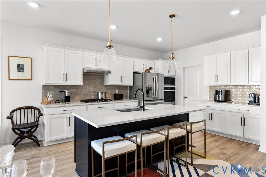 12906 Craftsbury Court, Midlothian, VA 23112 Modern kitchen featuring white cabinetry, a large center island with seating, stainless steel appliances, and wood-finish flooring