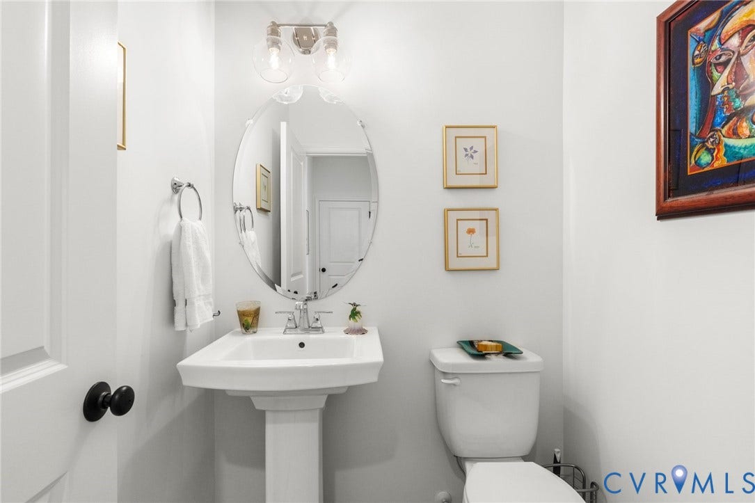12906 Craftsbury Court, Midlothian, VA 23112 Pedestal sink with chrome faucet, oval mirror, and three-bulb vanity light fixture