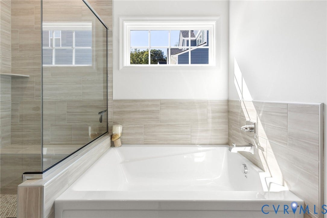 12906 Craftsbury Court, Midlothian, VA 23112 White soaking tub with chrome fixtures, framed window, and glass-enclosed shower featuring light-toned tile work
