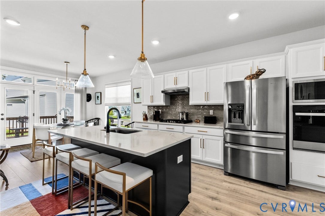 12906 Craftsbury Court, Midlothian, VA 23112 Spacious kitchen featuring an island with a light-toned countertop, white cabinetry with gold-toned hardware, stainless steel appliances, and wood-finish flooring