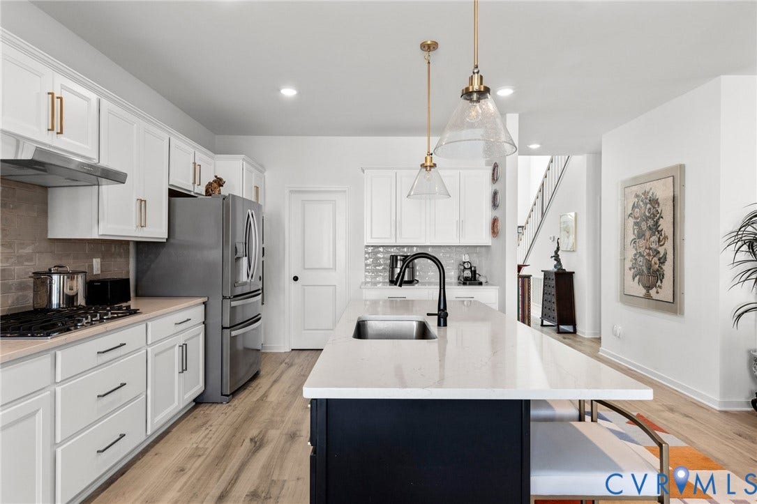 12906 Craftsbury Court, Midlothian, VA 23112 Modern kitchen featuring white cabinetry, stainless steel appliances, a large center island with a sink, and wood-finish flooring